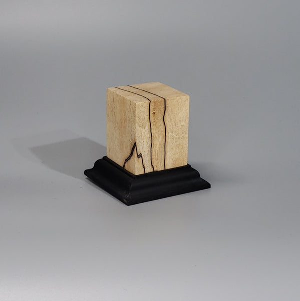 a wooden block with a black base on a gray background